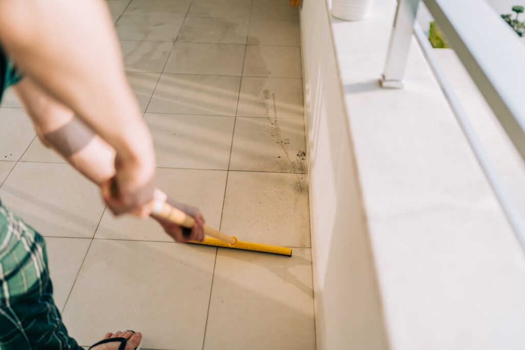 Dirty grout lines being cleaned with a grout brush